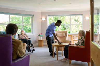 Nurse handing care resident coffee